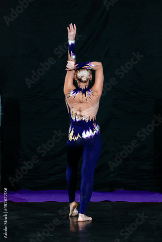 girl dancer stands with her back with her hand raised above her head