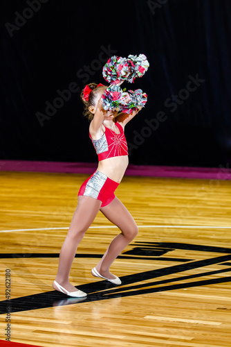 cheerleader girl covering her face with pom-poms
