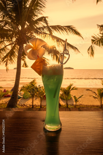 Refreshing cocktail on the background of an orange tropical sunset. Relaxing evening. Summer, exotic vacations.