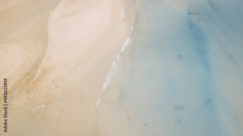 Vertical view of sand and beach with blue clean sea water. Tropical aerial landscape with waves and ocean. Seascape and amazing travel destination concept. Summer holiday vacation
