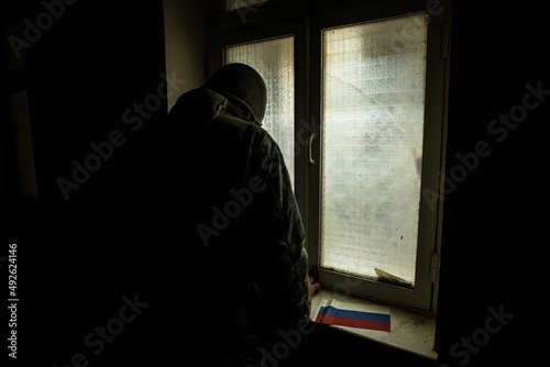 Conceptual photo of war between Russia and Ukraine. Ukraine and Russia flags on windowsill at night. Old creepy room with window.