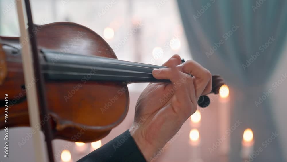 A Young Girl And Man Plays The Violin In A Beautiful Retro Room With Flowers And A Piano. A Young Girl And Man Plays The Violin In A Beautiful Retro Room With Flowers And A Piano.