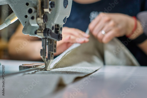 Fotografia, Obraz Process of a seamstress sewing beige fabric in a sewing workshop