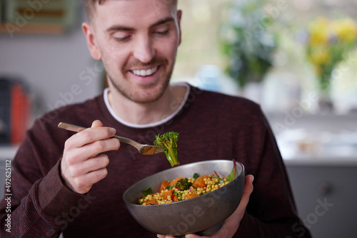 Close Up Of Man Eating Healthy Vegan Lunch In Kitchen At Home