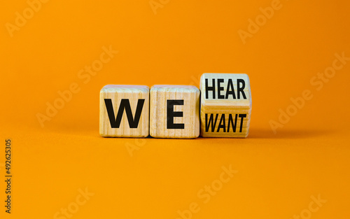 We want and hear you symbol. Turned the wooden cube and changed concept words we want to we hear. Beautiful orange background, copy space. Business support we want and hear you concept.