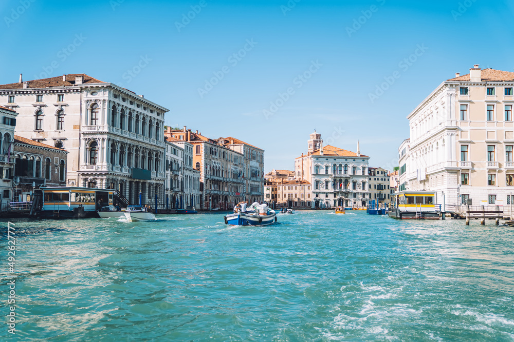 Motorboat floating on clear waters of Grand Canal in romantic Venice during bright summer daytime, landscape with ancient architecture buildings located in historic center of Italian city