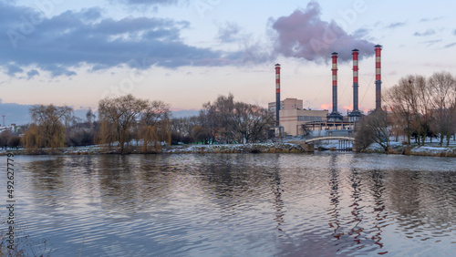 Power station with reservoir in winter. Beautiful seaside winter sunset with a smoking factory chimney.
