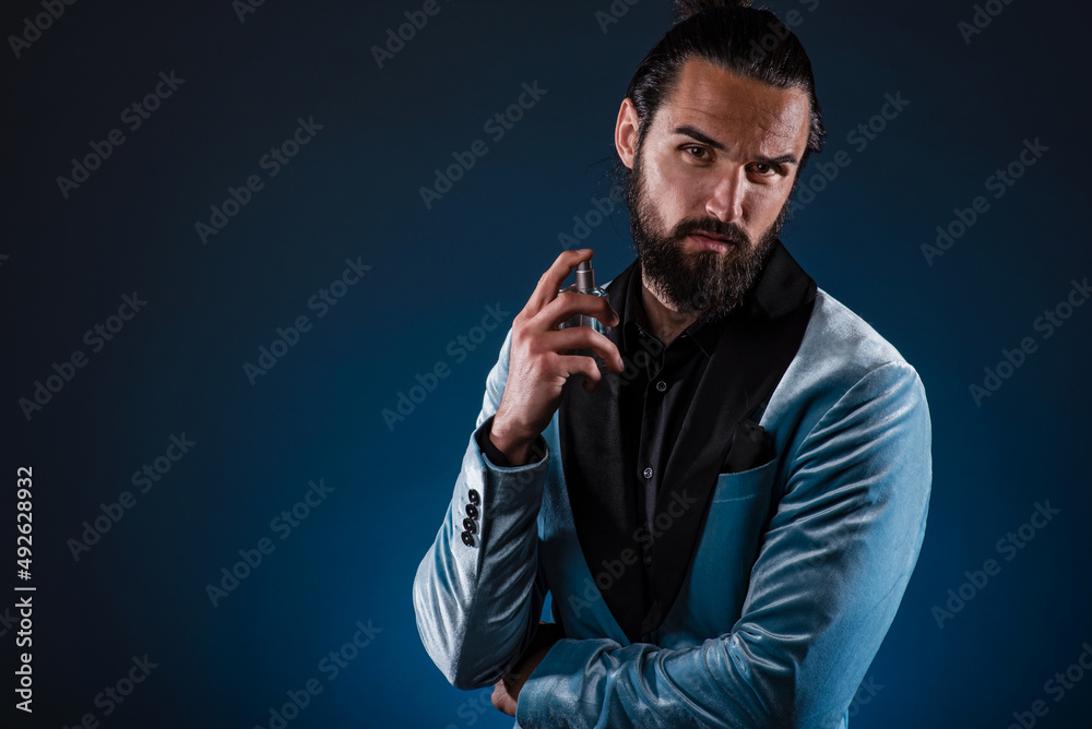 Masculine bearded young man holding a generic bottle of perfume. Male fragrance and perfumery, cosmetics. Masculine perfume. Bearded man holding a bottle of perfume Masculine bearded young man holding a generic bottle of perfume. Male fragrance and perfumery, cosmetics. Masculine perfume. Bearded man holding a bottle of perfume