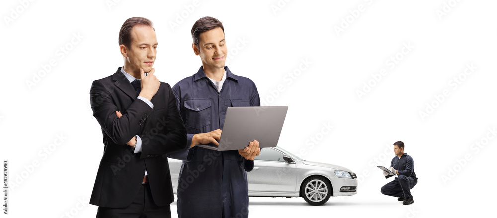 Auto mechanic and a businessman looking at a laptop computer and other mechanic repairing a car Auto mechanic and a businessman looking at a laptop computer and other mechanic repairing a car