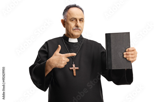 Mature priest holding a bible and pointing