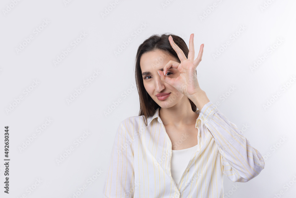 Close up portrait of attractive quirky young woman making binoculars with hands showing ok gesture on white studio background. Close up portrait of attractive quirky young woman making binoculars with hands showing ok gesture on white studio background.