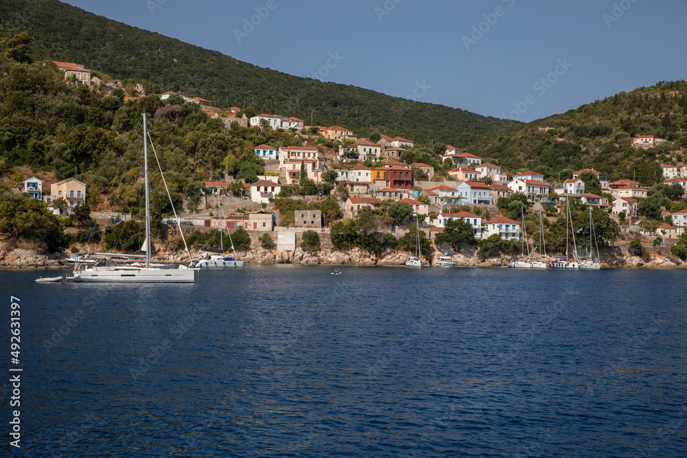 View of colorful houses and anchored sailing boats off the coast of the ITHACA island, KIONI Bay, Ionian Islands, Greece in summer sunny day.