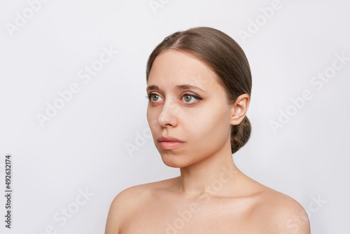 Portrait of a young attractive caucasian blonde woman with makeup isolated on a light gray background. A model with even proportional facial features. Natural beauty and fashion. Skin care