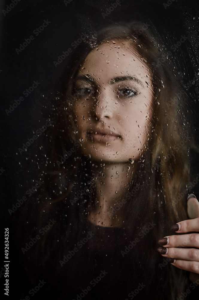 Blurred by the droplets - Beautiful long haired young woman holding a glass plate covered with droplets in front of her face, focus on droplets
