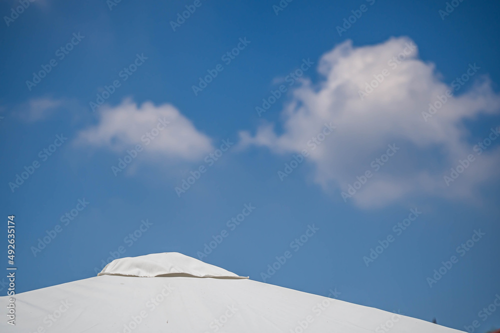 White house roof tiles with gradient blue sky background and white cloud