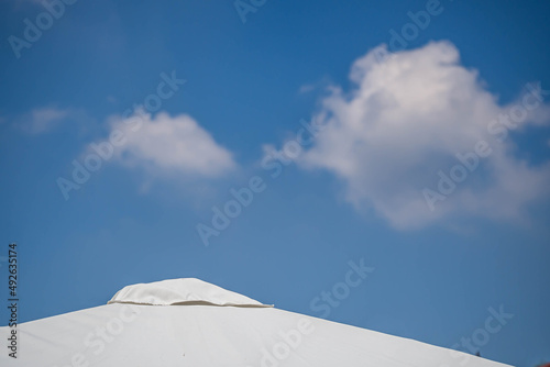 White house roof tiles with gradient blue sky background and white cloud