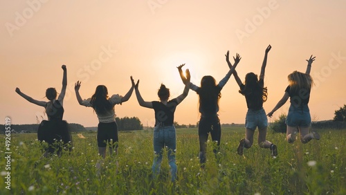 Girls friends are jumping against the background of an evening summer sunset.