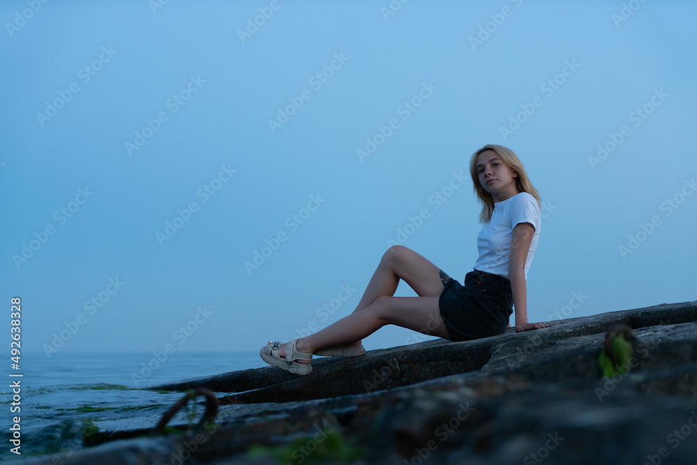 Young blonde woman on a rocky seashore after sunset. Odessa. Ukraine. Young blonde woman on a rocky seashore after sunset. Odessa. Ukraine.
