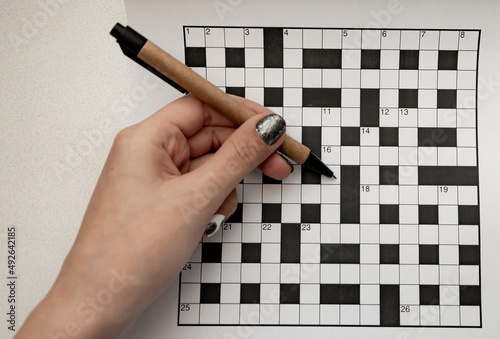 female hand holds a recycled pen in her hands and rejoices a crossword puzzle top view free space