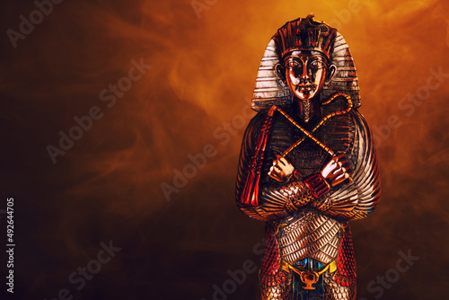 Egyptian pharaoh figurine in orange smoke on a black background.