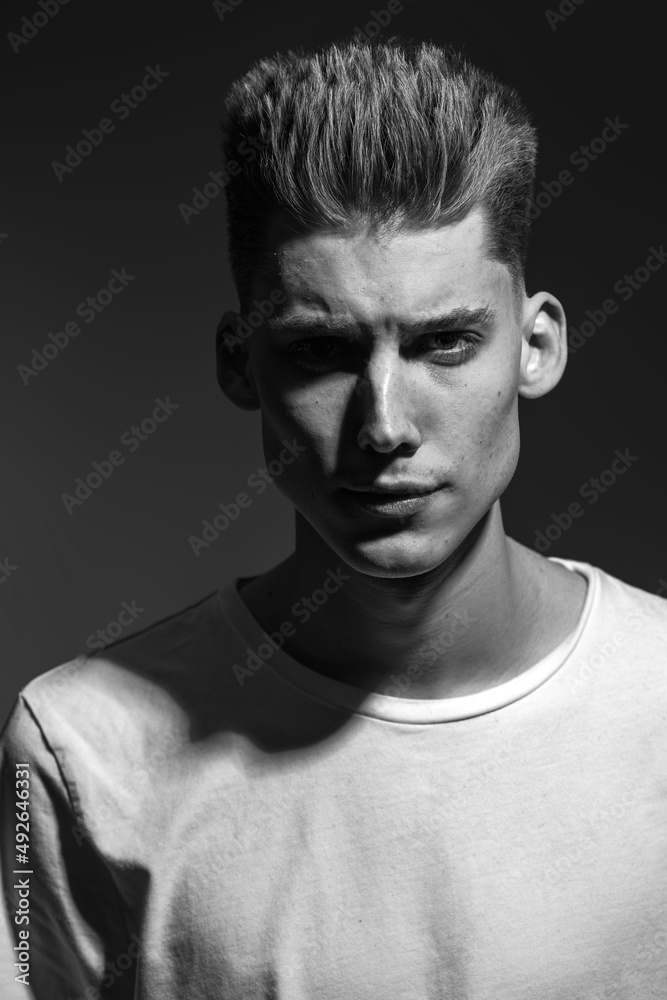 Naklejka premium Male beauty concept. Portrait of a fashionable young man with stylish haircut. Close up. Copy-space black and white image