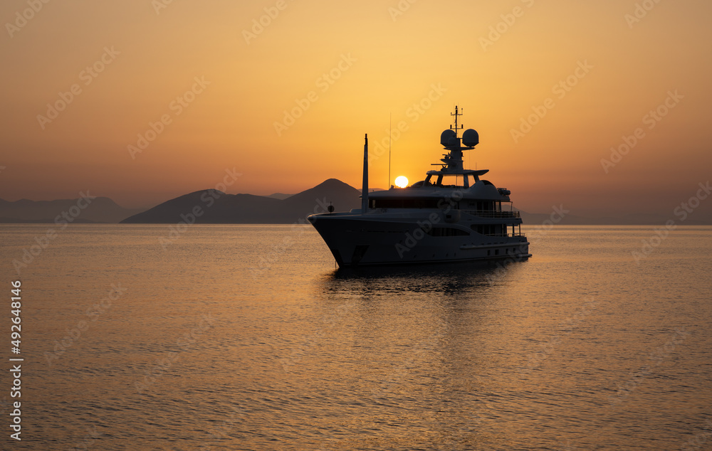 Anchored a luxury motor yacht off the coast of the ITHACA island, KIONI Bay, Ionian Islands, Greece in summer during the sunrise.