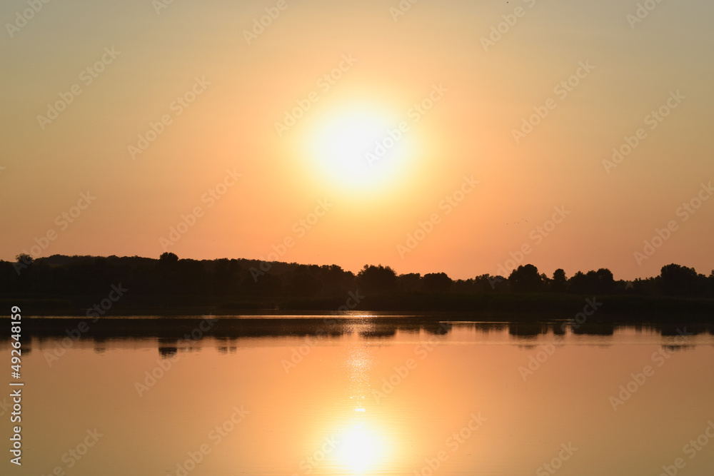Sunset over the river. Orange evening. Calm lake