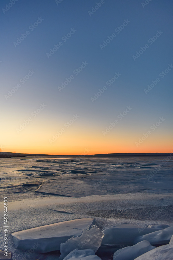Sunset horizon over frozen winter lake