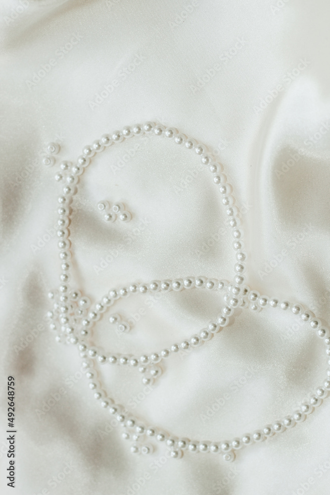 Pearl bijouterie beads on silk texture background. Pearl bijouterie beads on silk texture background.