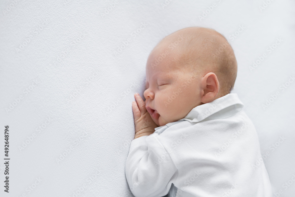 newborn baby boy in a suit sleeping on a light background. Top view newborn baby boy in a suit sleeping on a light background. Top view