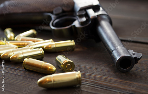 Historic Luger P08 Parabellum handgun, old soviet TT handgun and shiny 9 mm bullets on wooden vintage background