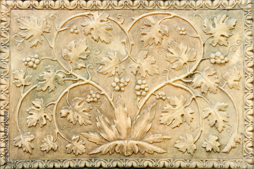 Relieve decorativo en terracota con hojas de parra y racimos de uvas. Panel de cerámica con adornos vitivinícolas. Fondo decorativo en una bodega