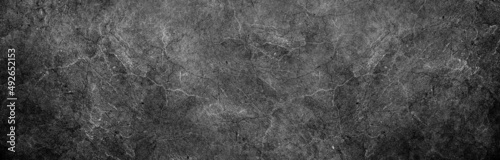 Dark black gray industrial background grunge stained marbled stone wall or rock surface texture with gritty grunge pattern and dark border in abstract black white website banner header backdrop design