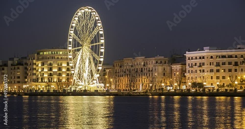 4K time lapse panoramic Night view of Illuminated giant Ferris wheel on the waterfront of Bari, region of Apulia, Italy. Puglia. Panorama