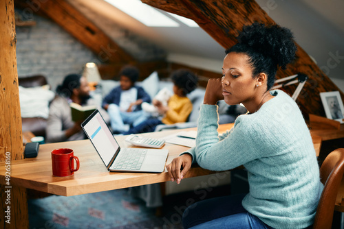 Foto Distraught black mother thinks of something while working at home