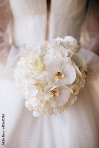 The bride holds a wedding bouquet of white orchids. Wedding decor ideas