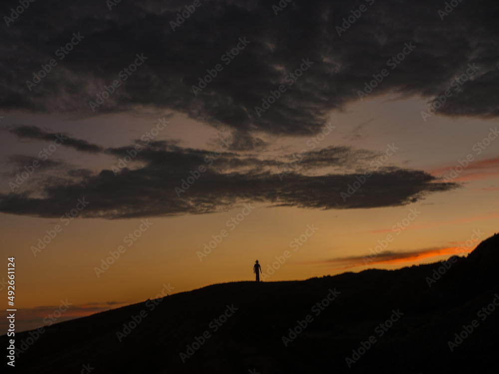 A person standing on a hill at sunset