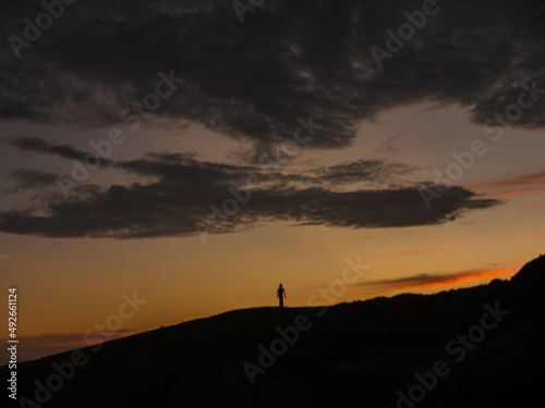 A person standing on a hill at sunset