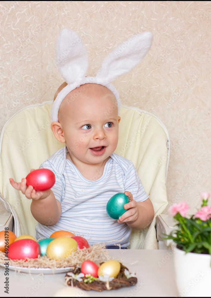Cute baby boy wearing bunny ears, smiling and holding colored Easter eggs in hands. Cute baby boy wearing bunny ears, smiling and holding colored Easter eggs in hands.
