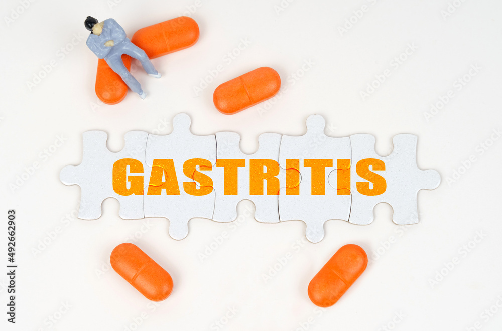 On the white surface of the tablet, a miniature human figure and puzzles with the inscription - GASTRITIS On the white surface of the tablet, a miniature human figure and puzzles with the inscription - GASTRITIS