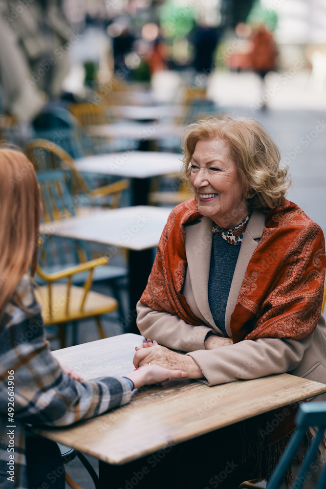 A grandmother bonding with her granddaughter while sitting in cafe and holding hands. A grandmother bonding with her granddaughter while sitting in cafe and holding hands.