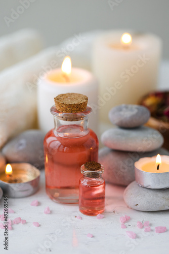 Concept of spa treatment in salon. Natural organic oil, towel, candles as decor. Atmosphere of relax, serenity and pleasure. Anti-stress and detox procedure. Luxury lifestyle. White wooden background