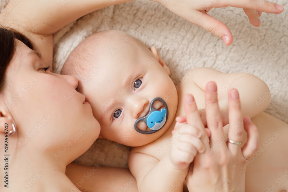 a mother kisses the baby on the bed. maternal and child health. a mother kisses the baby on the bed. maternal and child health.
