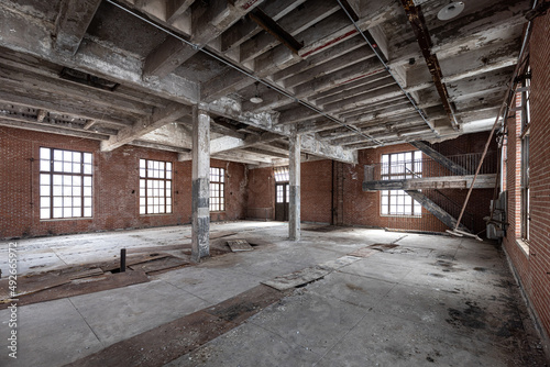 Inside an empty spacious dirty old abandoned industrial building with peeling paint and floor tiles coming up