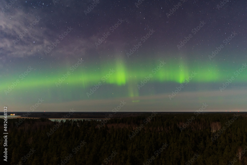 Aurora borealis, The Northern lights at the lake Usma and forest, Latvia. Aerial view.