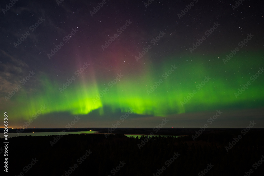 Aurora borealis, The Northern lights at the lake Usma and forest, Latvia. Aerial view.