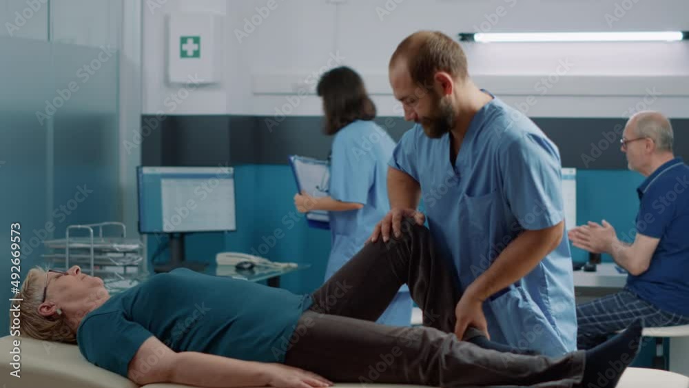 Osteopath cracking leg bones to heal old woman with mechanical disorders, using stretching and alternative medicine at physiotherapy appointment. Physical therapy procedure on patient. Osteopath cracking leg bones to heal old woman with mechanical disorders, using stretching and alternative medicine at physiotherapy appointment. Physical therapy procedure on patient.