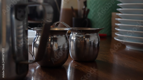 two metal coffee cups on a wooden table inside a coffee shop in tulum mexico