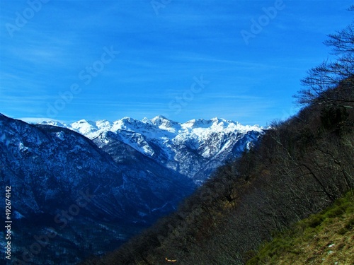Scenic winter view of snow covered mountains Mahavscek and Tolminski Kuk rising above Bohinj valley taken from Vogar in Triglav national park and Julian alps, Gorenjska Slovenia