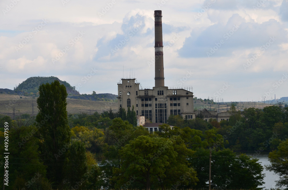 Industrial landscape with a view of the building of a non-working power plant and a mine waste heap in the background.